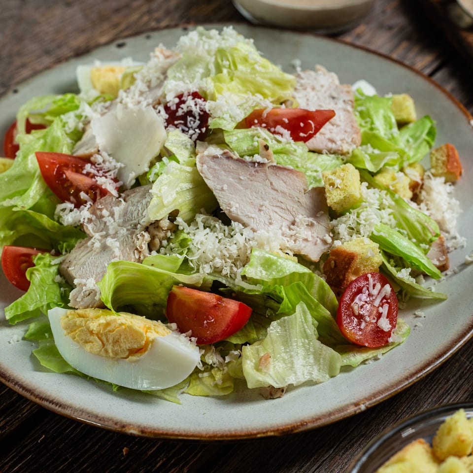 Rosella's Pizzeria's Caesar salad with chicken, tomatoes, hard-boiled egg, croutons, and parmesan cheese.